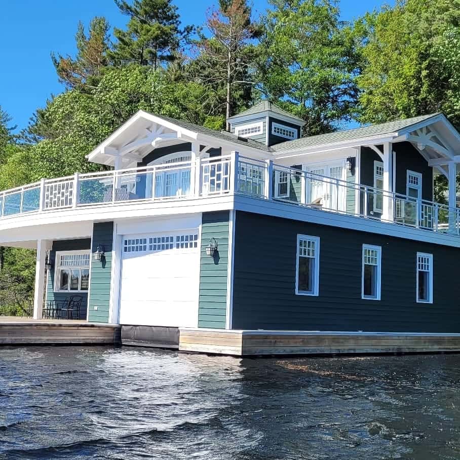 Green boathouse with white trim, lattice railing panels and upper deck in the sun