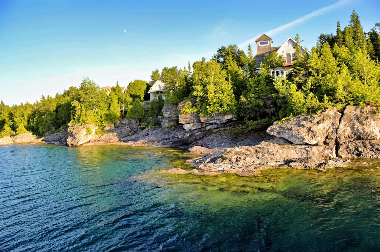 Home with a lookout set in the trees above a rocky Canadian shoreline and clear water
