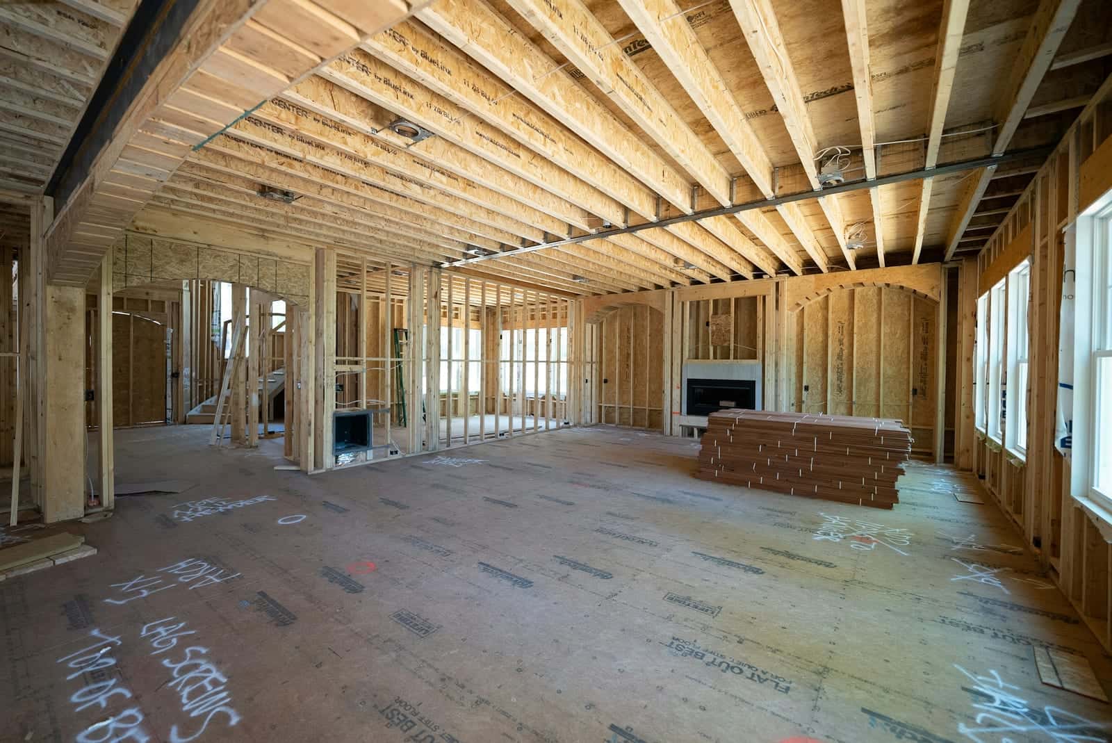 Interior of a house under construction with open stud walls and floor joists overhead